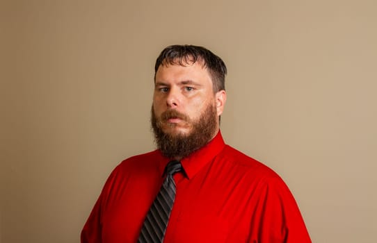 A man with a beard and a red shirt and a black tie.