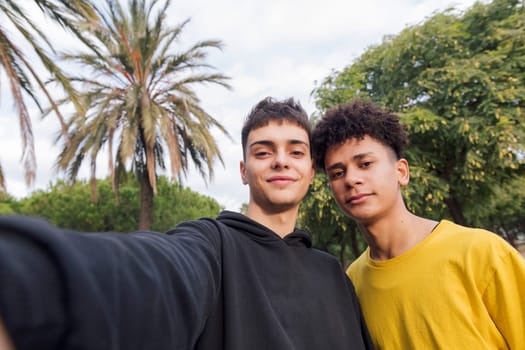 selfie photo of two multiethnic teenagers laughing happy looking at camera, concept of youth lifestyle and technology of communication
