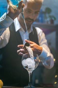 Professional barman in a white shirt and black apron making beautiful cocktail at party in nightclub. Nightlife. High quality photo