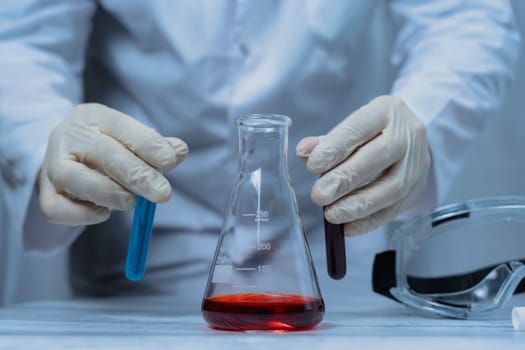 A scientist holds a test tube filled with green liquid in a laboratory, surrounded by various lab equipment. The image highlights the focus and precision involved in scientific research