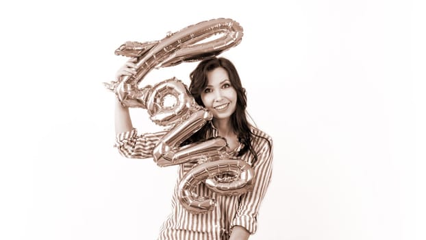 Smiling woman holding a gold balloon in the shape of the word love. Colour of the year Mocha Mousse.