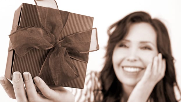 Joyful Woman with a Large Gift Box Tied with Ribbon, Radiating Happiness and Excitement. Colour of the year Mocha Mousse