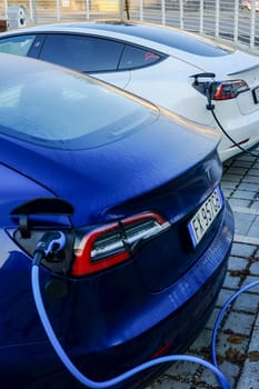 Cremona, Itally - October 6th 2024 Two tesla model 3 electric vehicles are charging their batteries at a public charging station, showcasing sustainable transportation and eco-friendly technology