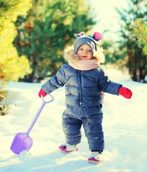 Winter little child playing with shovel toy in snow