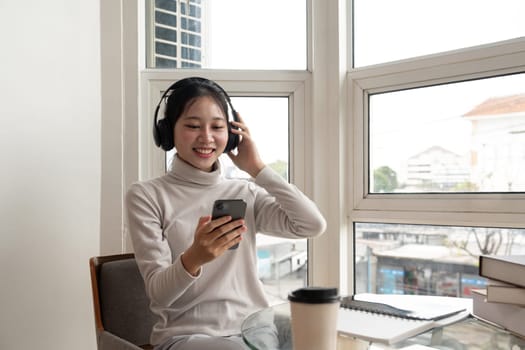 Asian beautiful woman smile at home in headphones. young woman listen music on smartphone at home. Use technology, lifestyle concept.