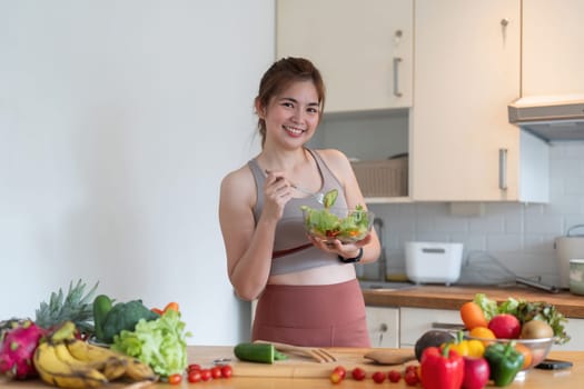 Young woman standing in the kitchen making a salad for health.