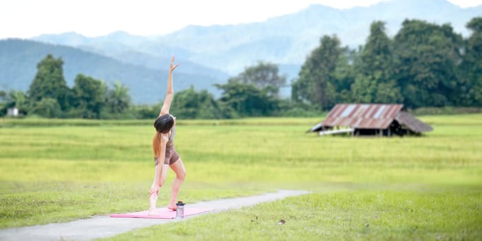 Healthy women doing yoga in the morning In the middle of a rice field . concept healthy and outdoor activity.