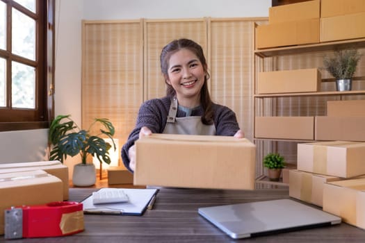 Young woman working online ecommerce shopping at her shop. Young woman seller prepare parcel box of product for deliver to customer. Online selling, ecommerce. Selling products online.
