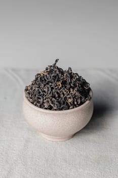 A beautiful closeup of a variety of dried tea leaves artfully displayed in a chic and stylish ceramic bowl