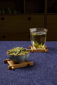 A beautifully serene and calming arrangement of dry green tea leaves alongside brewed tea in a cozy setting