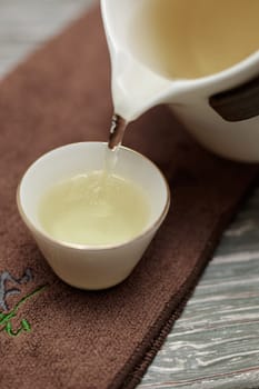 A serene and peaceful scene of tea being poured elegantly from a teapot into a fine cup on a textured background