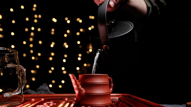 A serene moment of tea pouring into a traditional pot, captured in soft lighting with bokeh effects.
