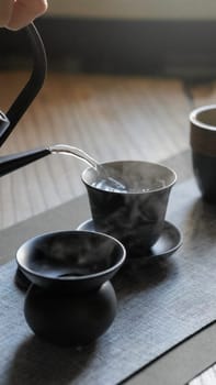 A tranquil scene of tea brewing that showcases elegant black ceramic teaware and steaming hot water