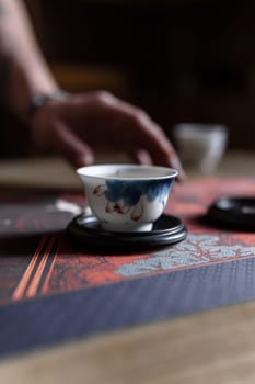 Savor the calmness while sipping a delightful cup of tea from a beautifully handcrafted vessel on a traditional surface