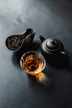 An elegantly serene composition showcasing tea leaves, a decorative teapot, and a glass filled with brewed tea