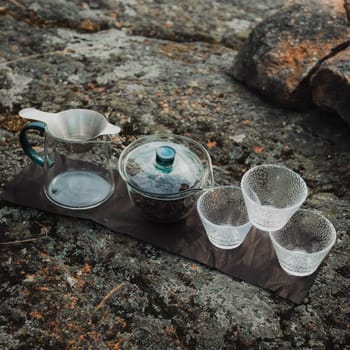 A serene tea setup situated on a rocky surface, showcasing elegant glassware designed for a perfect brew experience