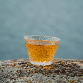 A closeup view of a beautifully filled, textured glass cup elegantly placed on a rugged stone surface