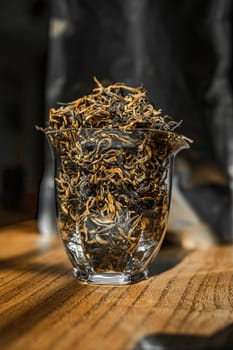 A colorful display of dried tea leaves arranged in a clear glass container on a rustic wooden table