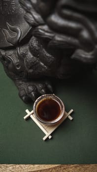 A serene image shows a steaming cup of tea on a wooden stand next to an intricate, beautiful sculpture