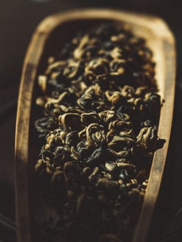 A close view of assorted dried herbs in a rustic wooden scoop, showcasing their natural textures and beauty