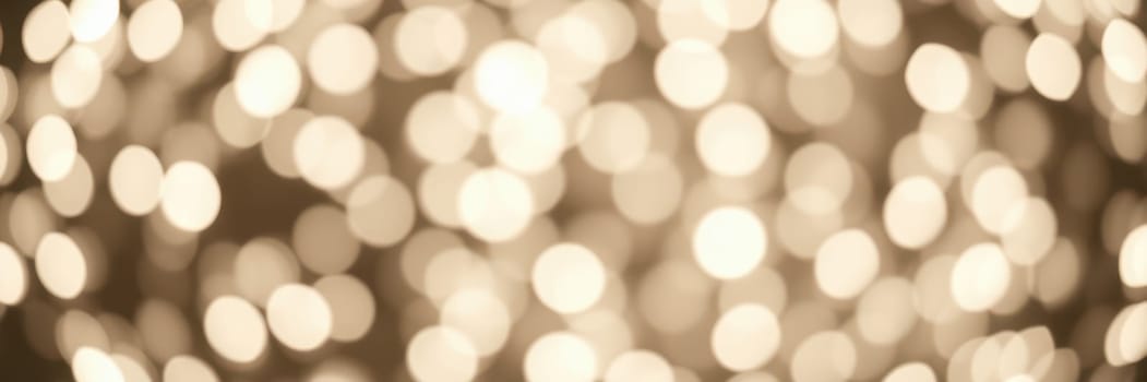 Warm golden lights illuminate a space with a soft bokeh effect, enhancing the cozy ambiance during a festive evening gathering. Guests enjoy the enchanting atmosphere.