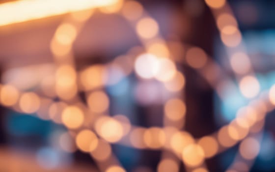 Blurry, softly glowing lights illuminate a cozy indoor environment, creating a warm atmosphere perfect for relaxation and socializing during the evening hours.