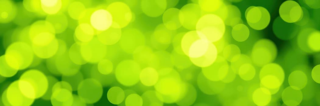 A stunning collection of green and yellow bokeh lights illuminates a natural landscape, enhancing the vibrant colors of leaves and plants under warm sunlight.