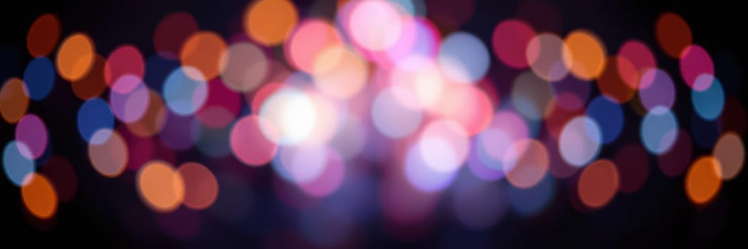 Bright and colorful bokeh lights fill the background, creating a lively and cheerful atmosphere during a nighttime event. The vibrant hues enhance the festive mood.