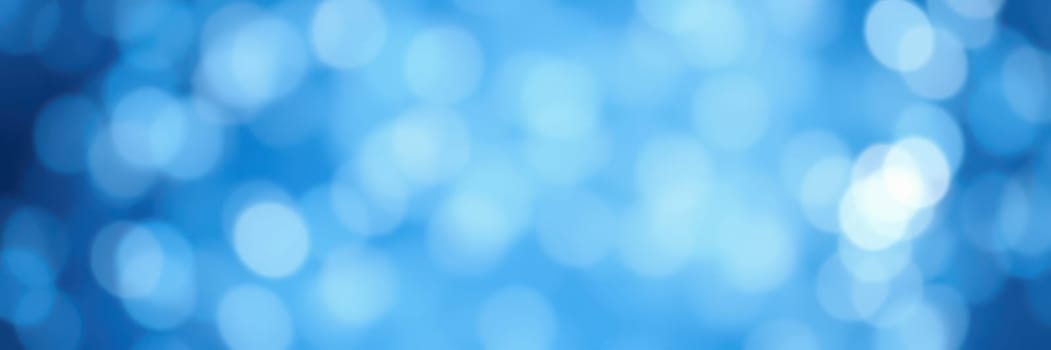 Soft blue bokeh lights form an abstract background that captivates with its dreamy effect, ideal for creative projects or digital designs. The vibrant hues blend seamlessly.