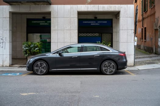 Lombardy, Italy - November 20th 2024 Side view of a parked mercedes eqs 580 4matic electric car in front of a building with a real estate agency sign