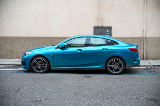 Lombardy, Italy - November 20th 2024 Stylish snapper rocks blue metallic bmw 218i gran coupe parked on a european city street
