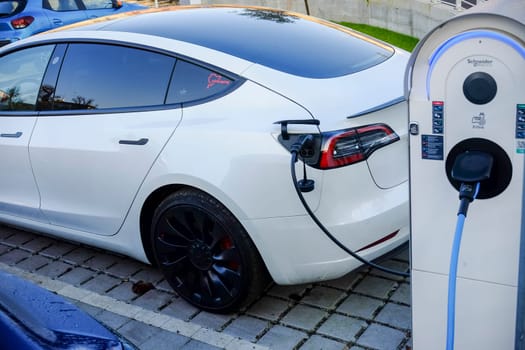 Cremona, Itally - October 6th 2024 White tesla model 3 long range dual motor charging its battery at a schneider electric charging station