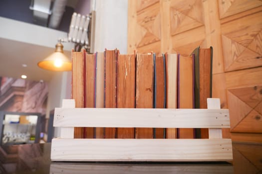 A wooden bookshelf with books, vase of orange flowers in front of a wooden panel wall