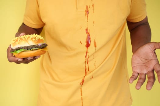 A spill of ketchup from a squeeze bottle on a yellow shirt resulted in a messy stain