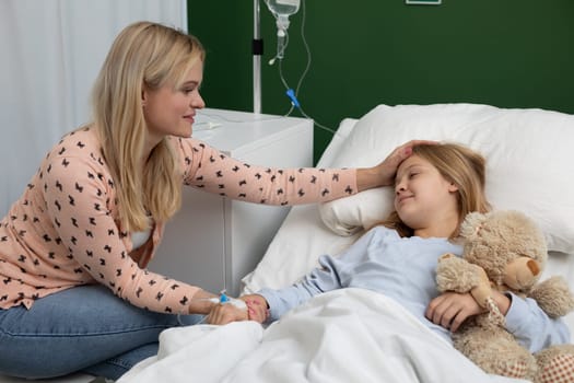 In a hospital, a caring mother comforts her sick daughter, showing unwavering support and affection