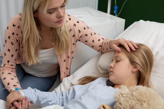 A loving mother holds her daughters hand, offering comfort and support during a tough hospital stay