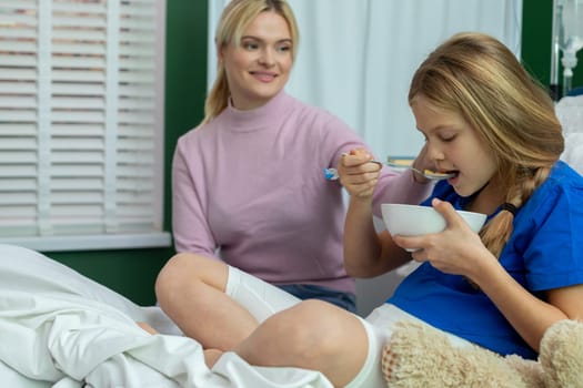 A compassionate caregiver feeds a young girl in a hospital, showcasing empathy and unwavering support