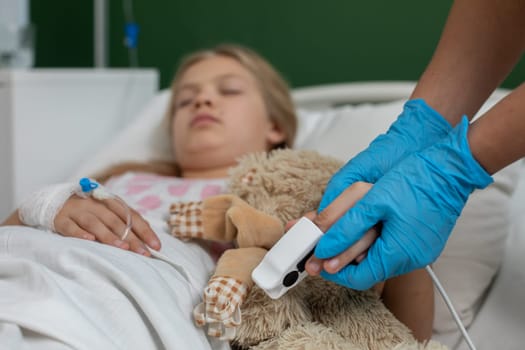 A child in a hospital bed receiving care, holding a comforting teddy bear, surrounded by medical monitoring equipment