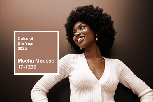 A stylish woman with natural curls smiles confidently in a light sweater against a warm backdrop. The color mocha mousse is highlighted as the trend for 2025, enhancing the atmosphere.