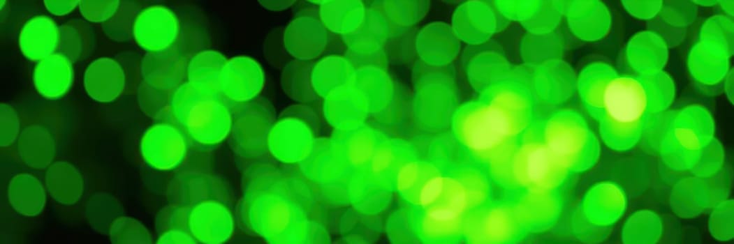 A vibrant array of green bokeh lights fills the background, creating a joyful and festive ambiance during an evening event or celebration. The lights sparkle softly against the dark backdrop.
