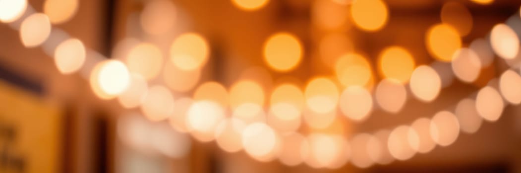 Warm golden lights illuminate a cozy indoor setting, creating an inviting atmosphere for a gathering. The soft glow enhances the ambiance as guests mingle and enjoy the moment.