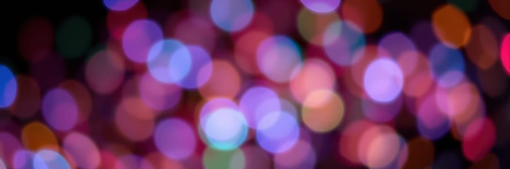 Bright, colorful bokeh lights illuminate the scene, creating a festive ambiance during a nighttime celebration in a lively outdoor location filled with joy and excitement.
