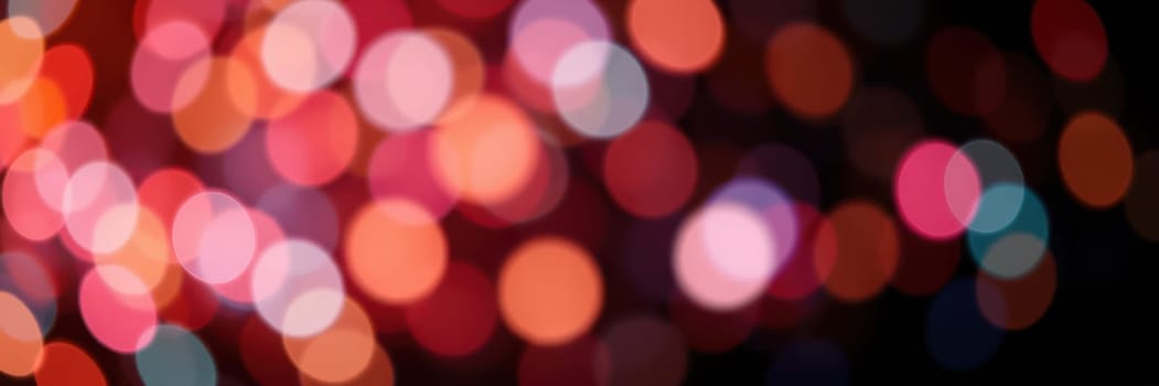 Vibrant bokeh lights in shades of red, pink, and blue illuminate the night, enhancing the joyful atmosphere of an urban celebration filled with excitement and energy.