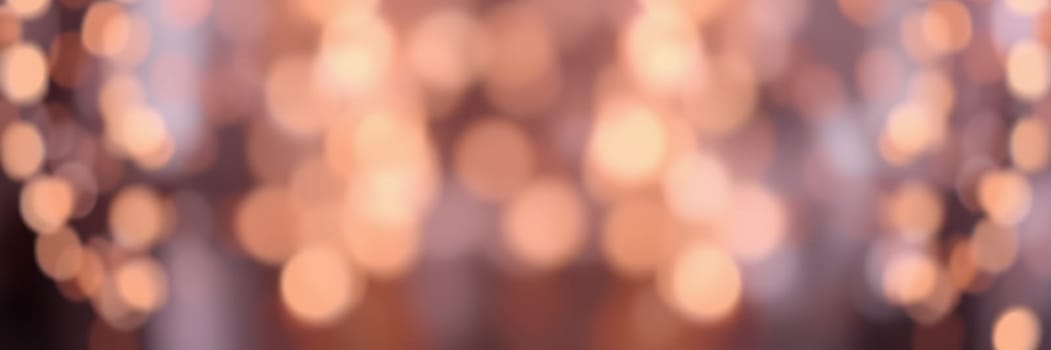 Colorful and soft lights illuminate a vibrant gathering, setting a warm, inviting mood. Guests engage in conversation and laughter, enjoying the evening.