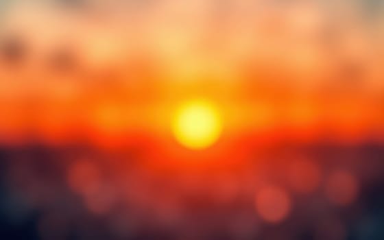A stunning sunset unfolds with vibrant colors blending in the sky. The sun sets on the horizon, surrounded by blurred clouds, creating a peaceful and tranquil ambiance.