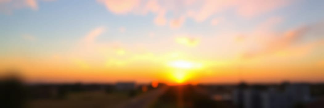 A breathtaking sunset captures the sky in shades of orange, pink, and purple, as the sun dips below a city skyline, marking the end of a peaceful day.
