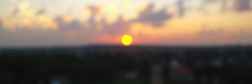 A vibrant sunset casts warm hues over the city skyline, with the sun dipping below the horizon, creating a serene atmosphere during evening hours.