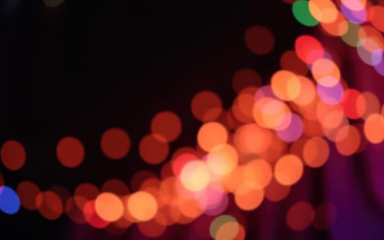 Colorful bokeh lights twinkle in a blurred background, creating a magical ambiance at an evening celebration in a bustling urban setting.