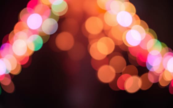 A multitude of colorful bokeh lights illuminates the area, creating a magical ambiance during a nighttime celebration. The soft glow enhances the festive spirit and joy.