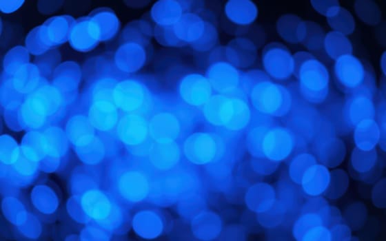 A multitude of soft blue bokeh lights shimmer, enhancing the ambiance at an evening event, creating a calm and inviting atmosphere for the guests.